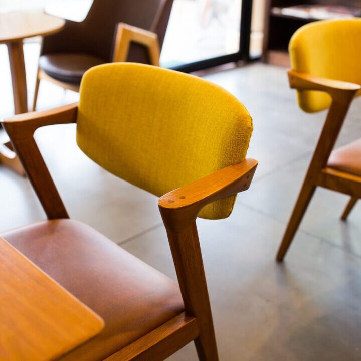 Yellow cushioned chairs around wooden tables in a cozy setting.