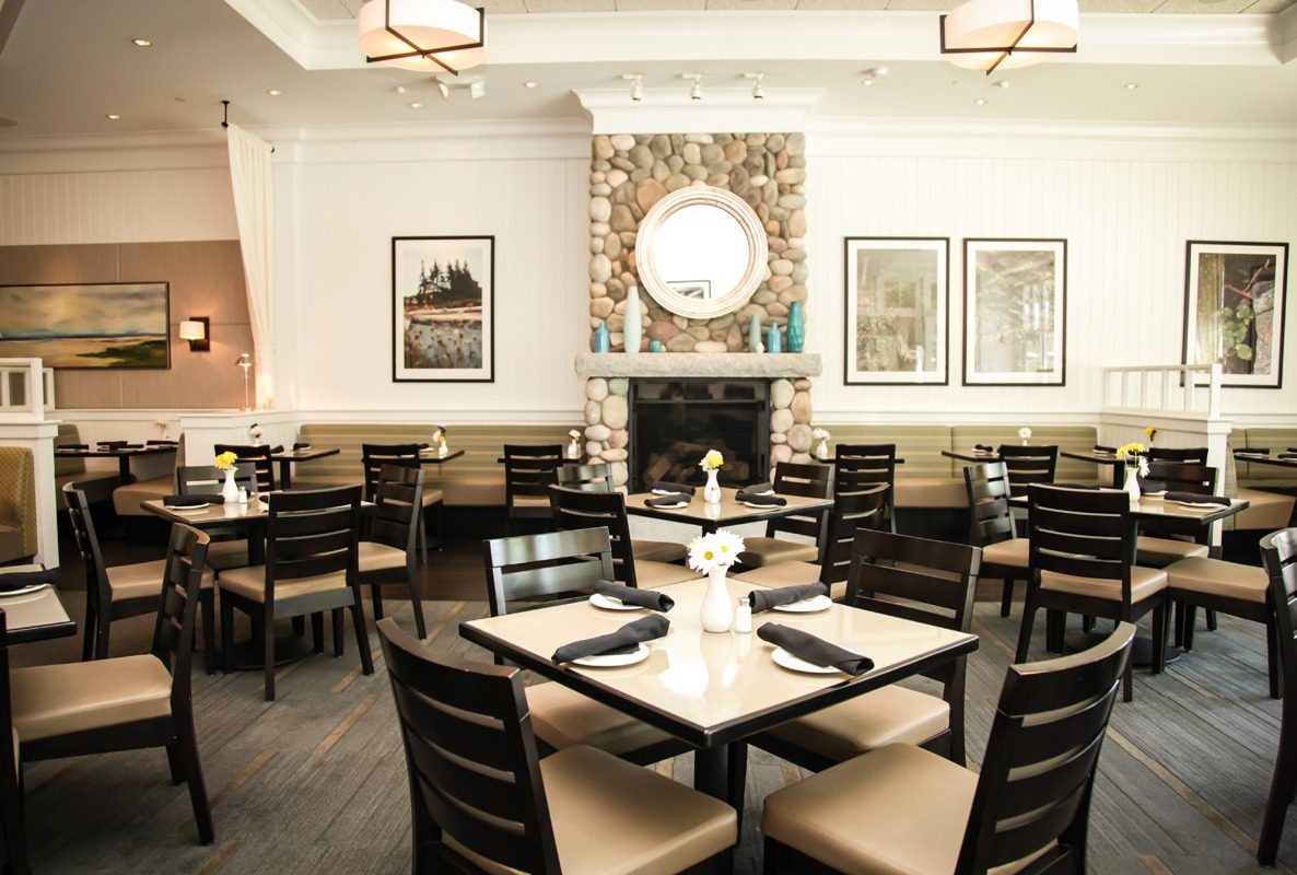 Elegant dining room with neatly arranged tables and a fireplace.