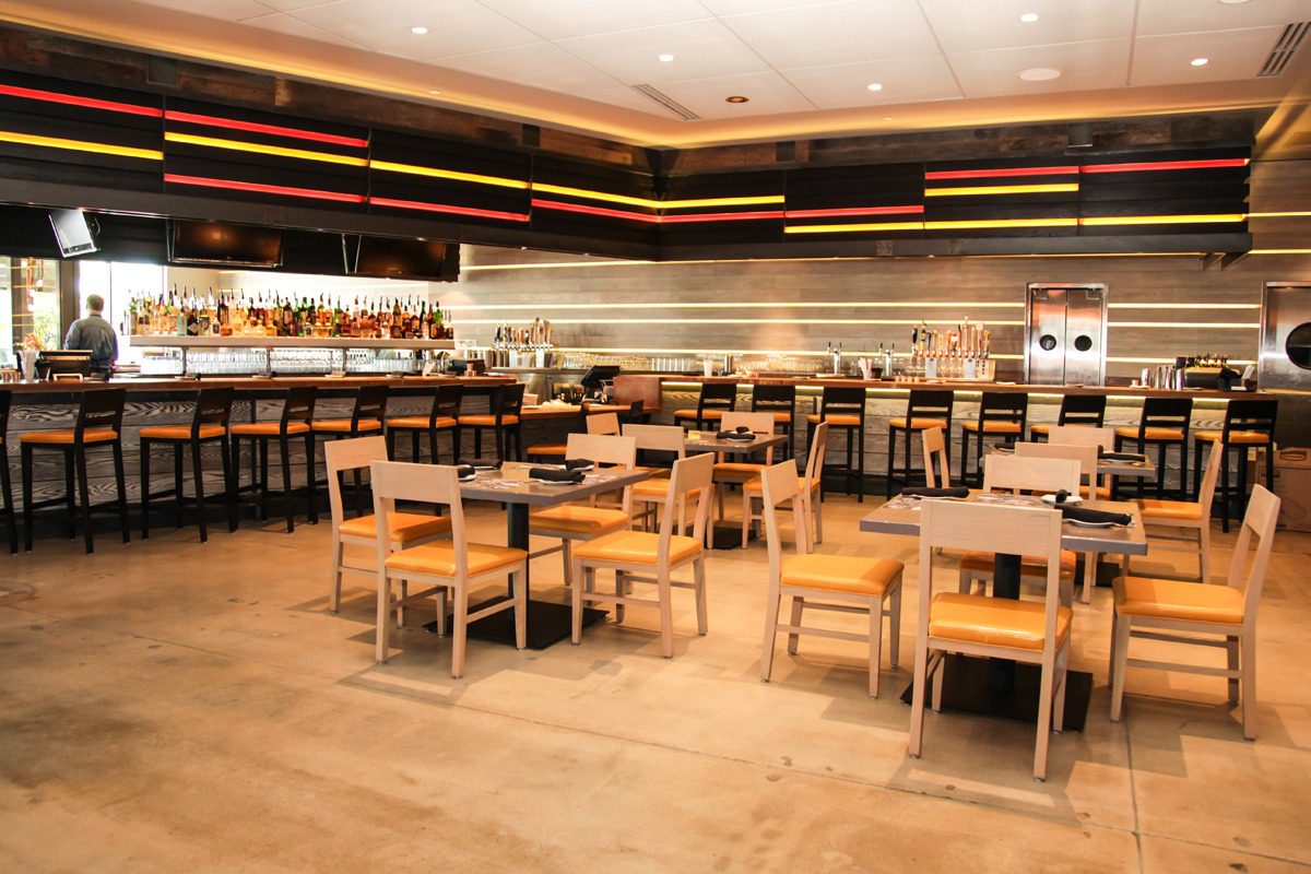 Spacious modern restaurant with wooden tables and chairs.