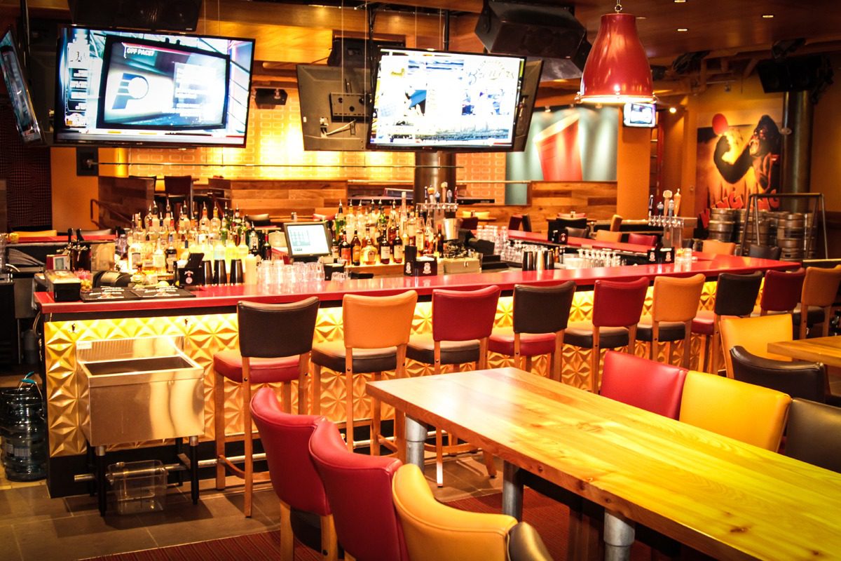 Cozy bar interior with wooden tables and colorful chairs.