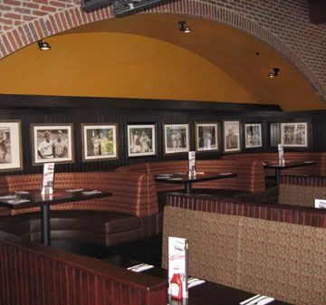Interior of a cozy restaurant with booth seating and framed art on the walls.