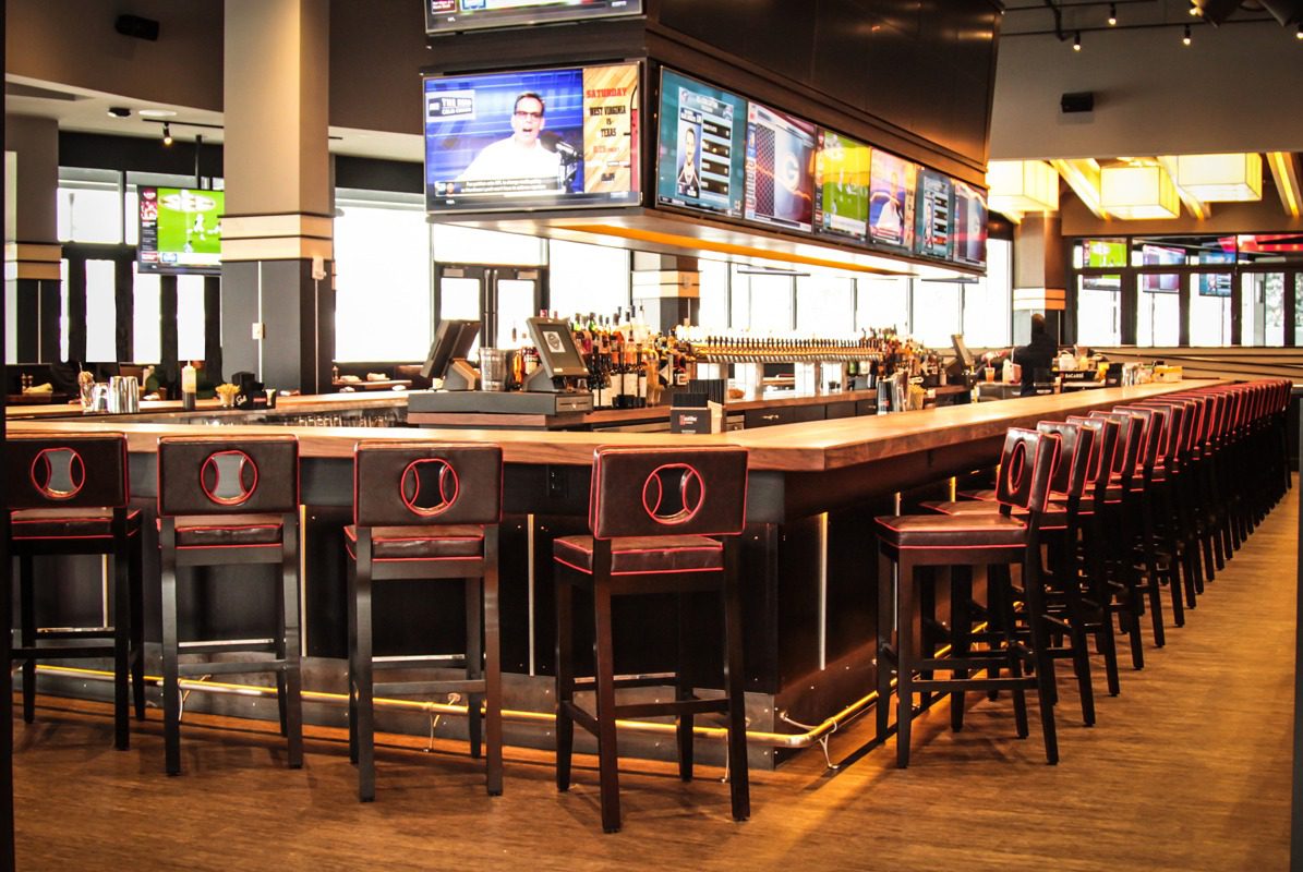 Empty bar with wooden stools and TVs above the counter.