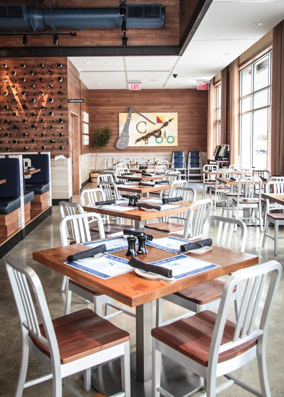 Bright, modern restaurant interior with wooden tables and white chairs.