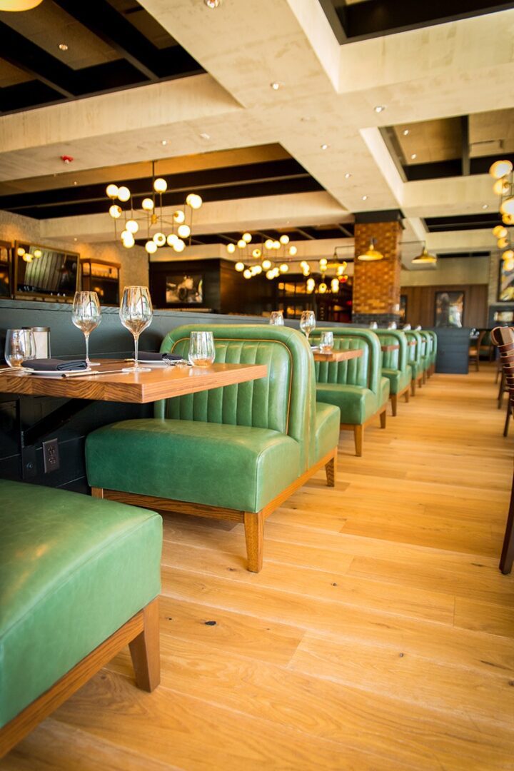 Cozy restaurant interior with green leather booths and warm lighting.