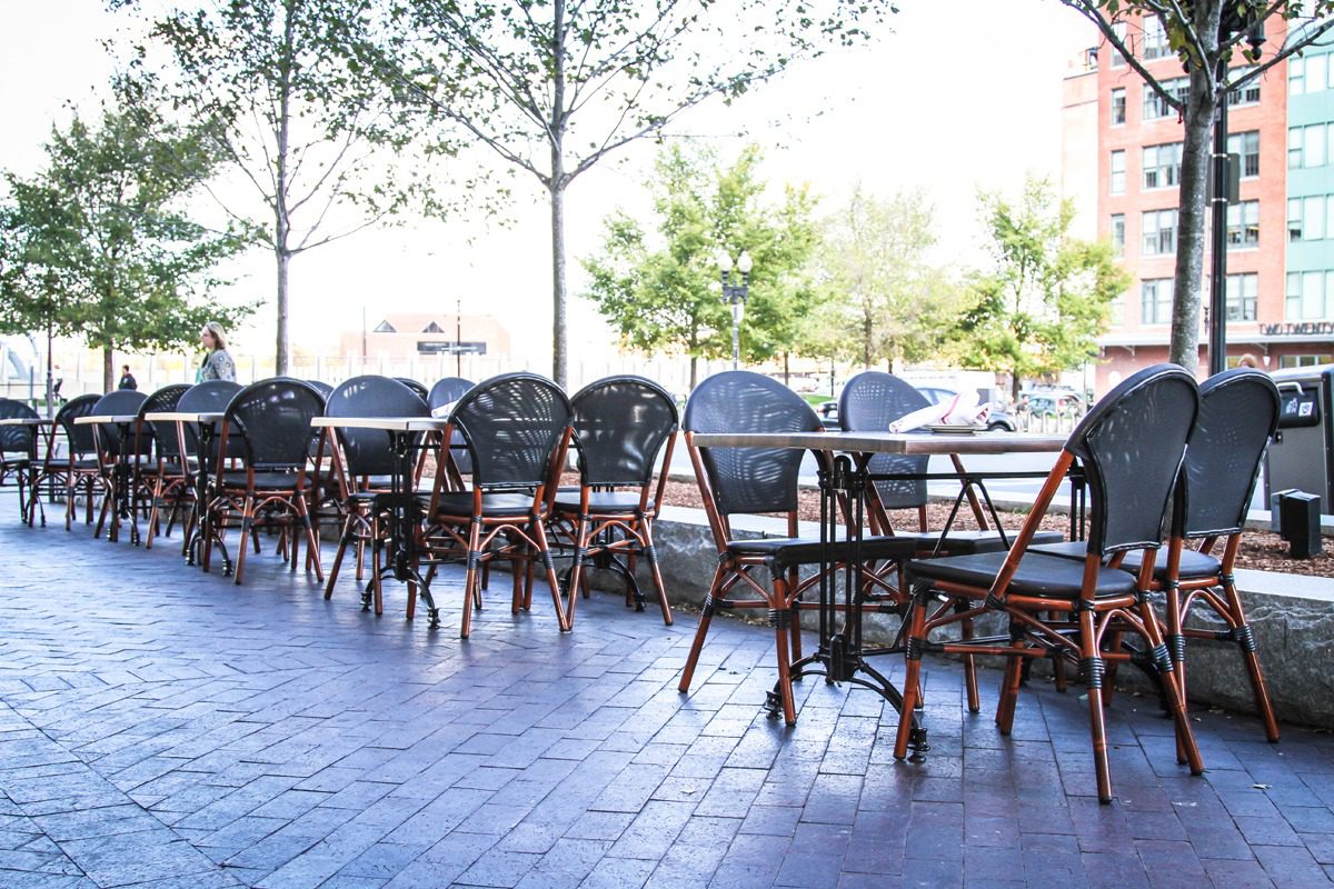Empty outdoor cafe seating with natural light and trees.