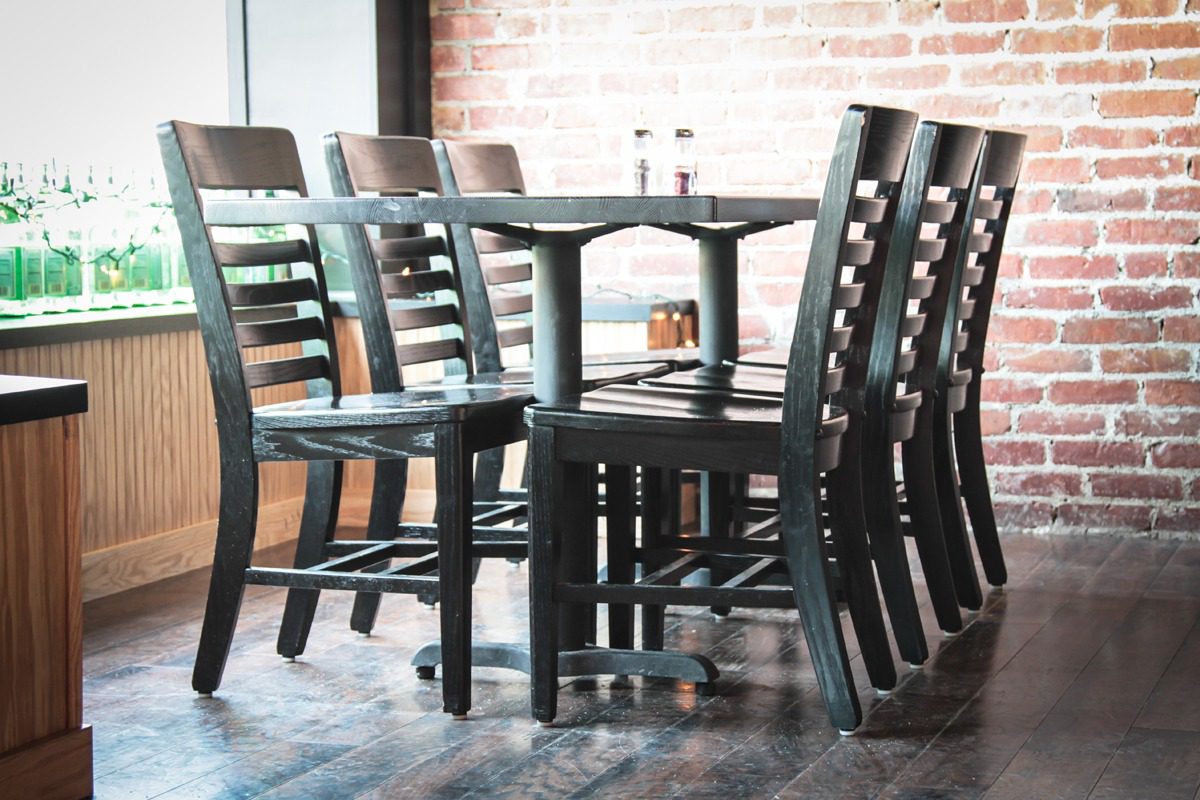 Empty wooden chairs and tables in a cozy cafe with brick walls.