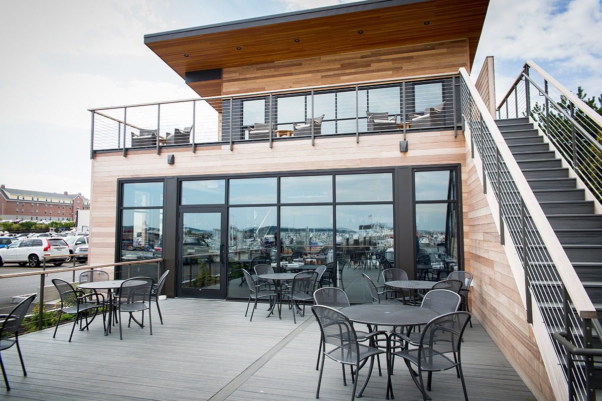 Outdoor patio with tables and chairs under a wooden overhang.