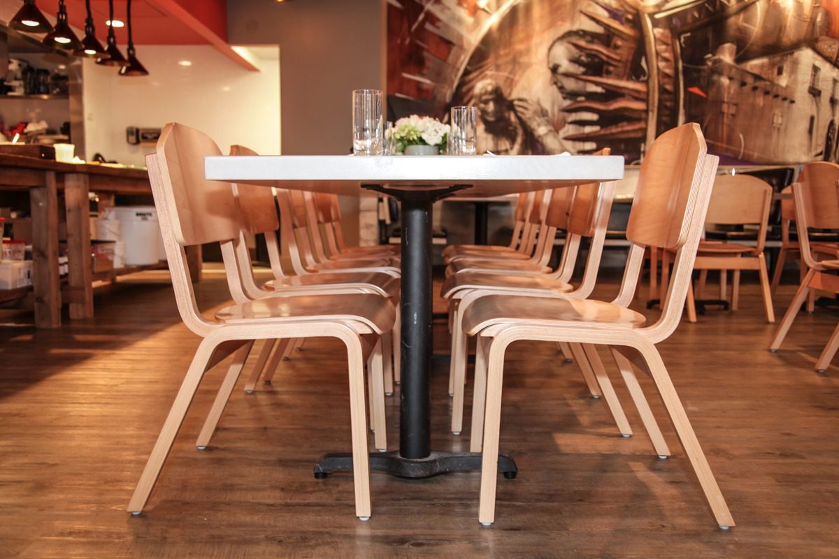 Modern wooden chairs neatly arranged around a white table in a cozy cafe.