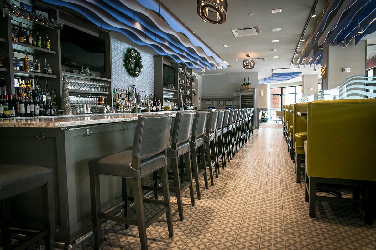 Modern bar with tall stools and stylish ceiling lights.