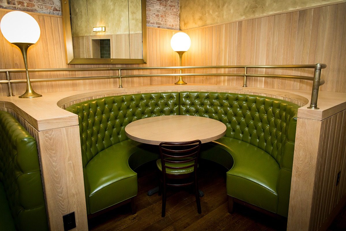 Cozy green booth seating around a circular table with warm lighting.