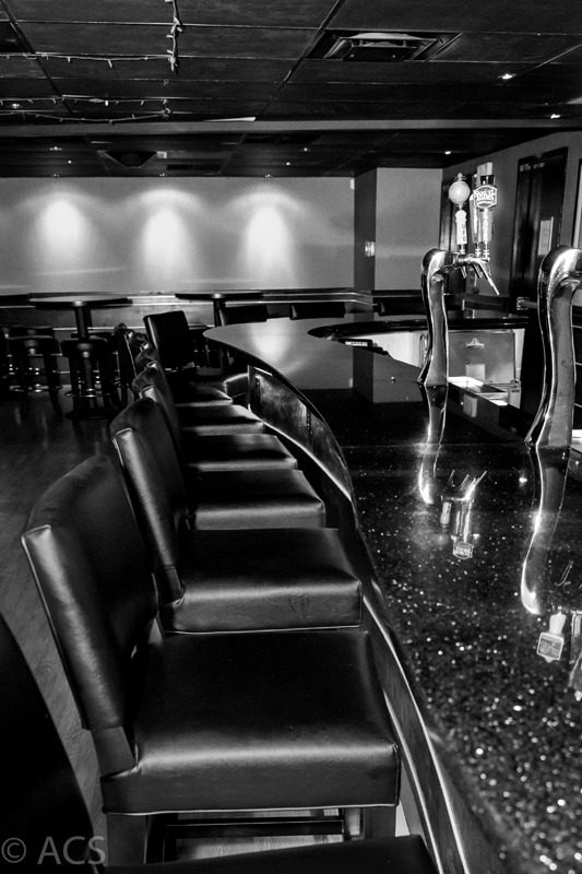Empty bar counter with high chairs in black and white.