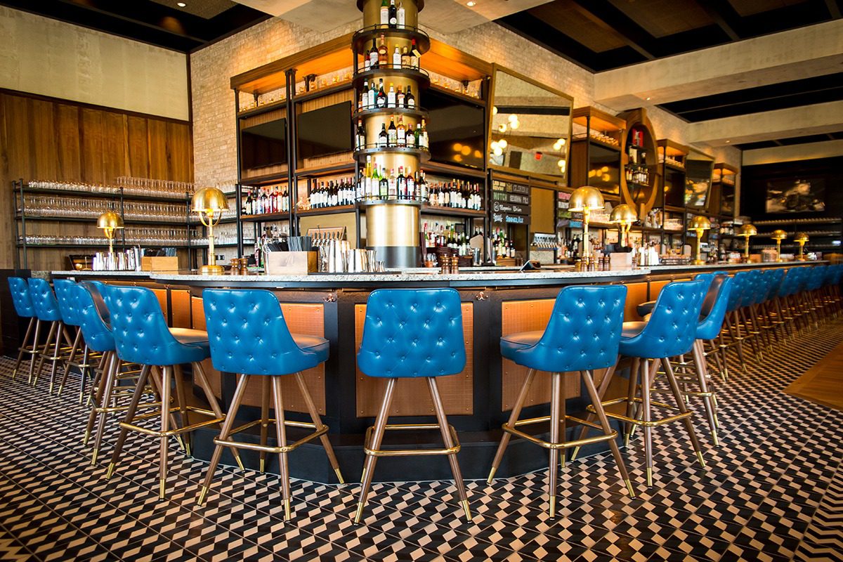 Stylish bar with blue chairs and patterned floor tiles.