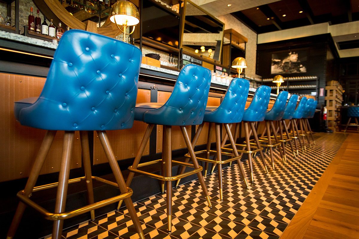 Row of vibrant blue bar stools with tufted backs at a stylish bar counter.
