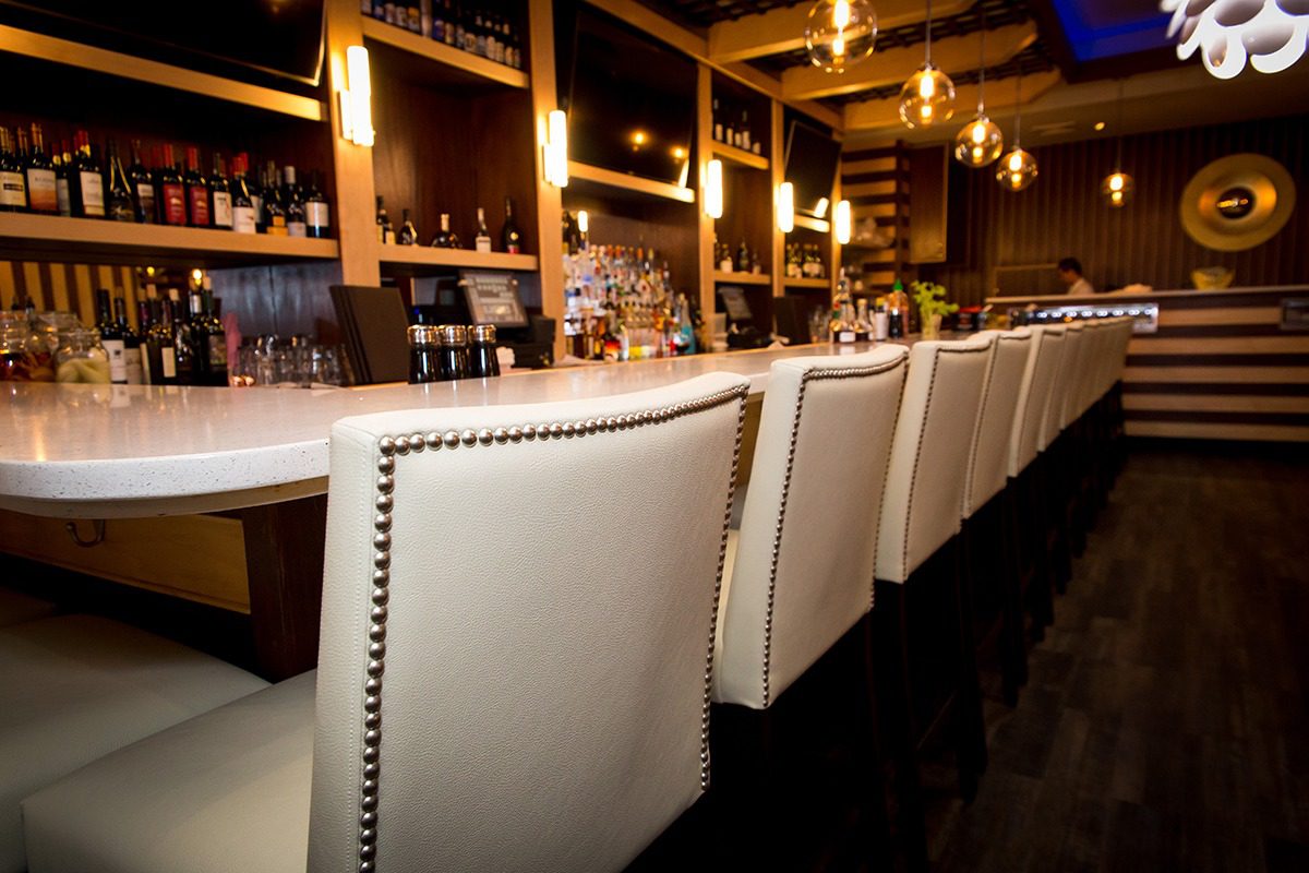 Elegant bar seating with white leather chairs and warm lighting.