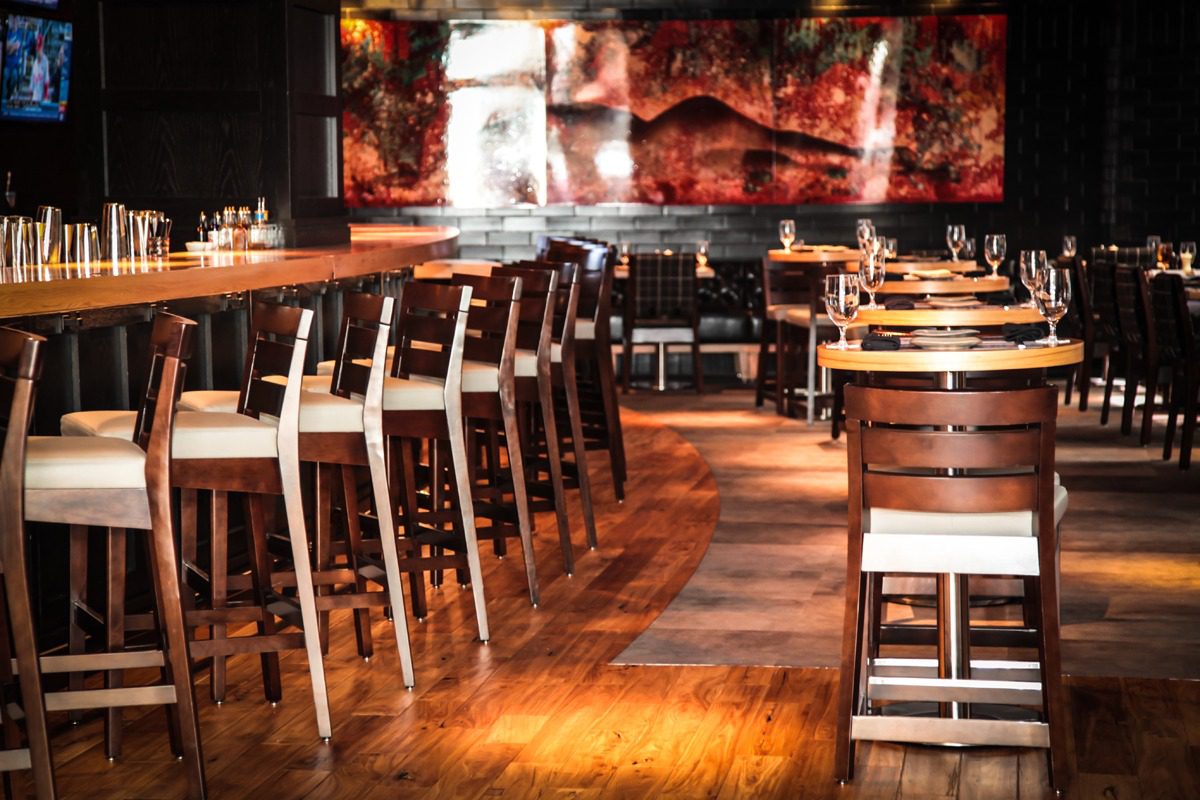 Cozy restaurant interior with wooden tables and chairs under warm lighting.