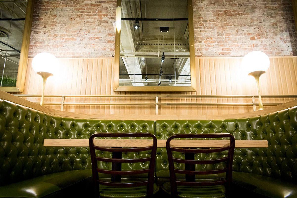 Cozy booth seating with green tufted upholstery and wooden chairs in a rustic restaurant.