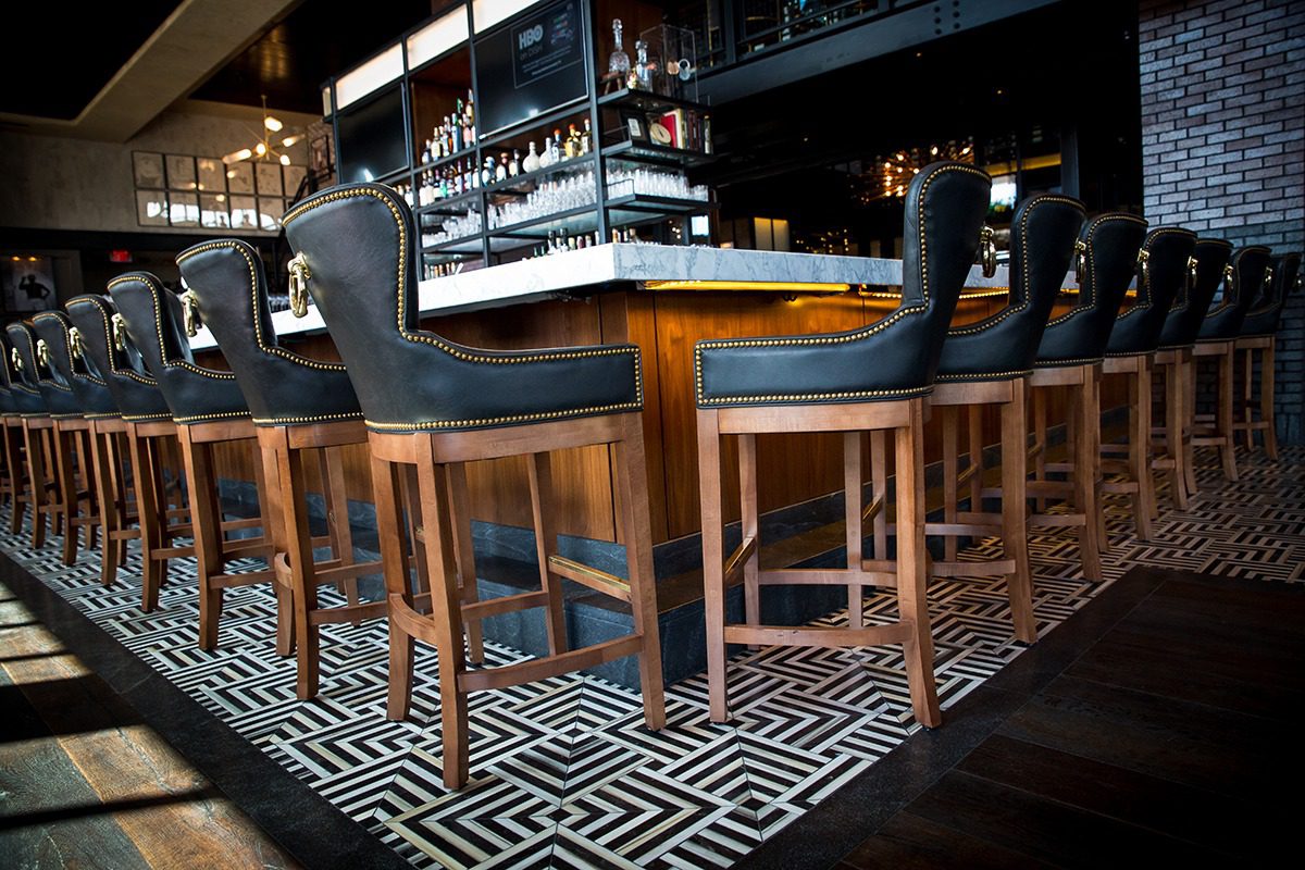 Elegant bar stools with dark upholstery and wooden legs at a stylish bar counter.