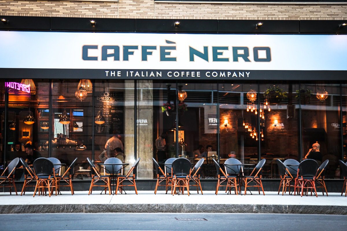 Caffè Nero coffee shop with outdoor seating and people inside.