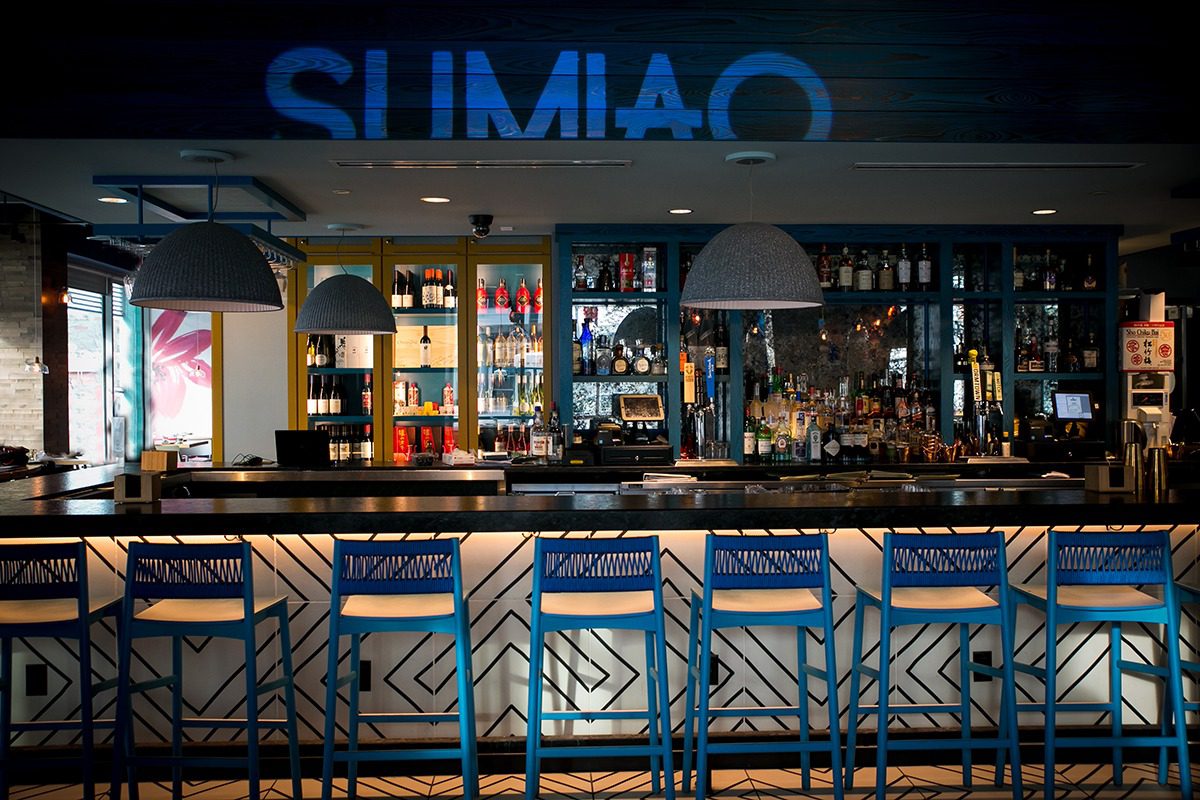 Modern bar interior with blue lighting and stylish seating.