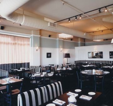 Elegant restaurant interior with black and white decor and neatly set tables.