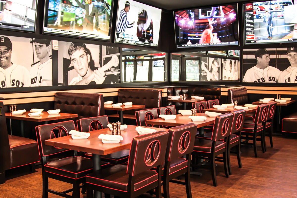 Modern sports bar with wooden tables and multiple TVs.