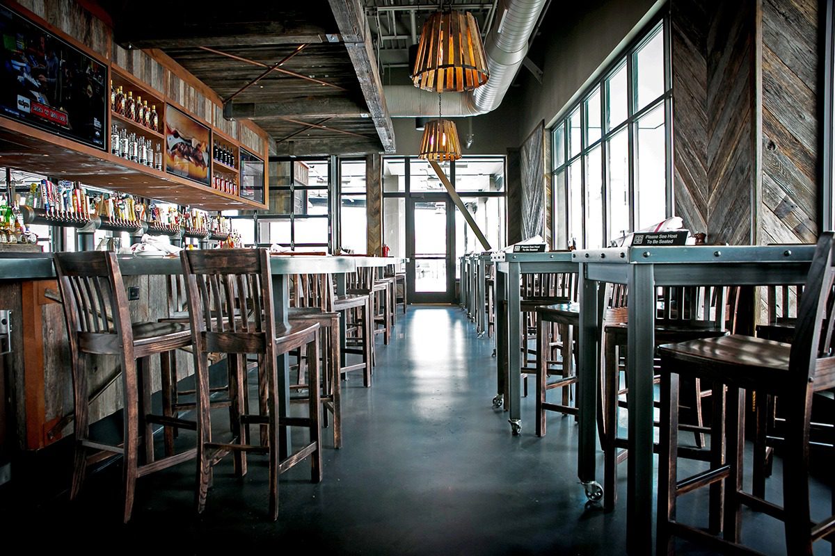 A cozy, empty cafe with wooden furniture and large windows.