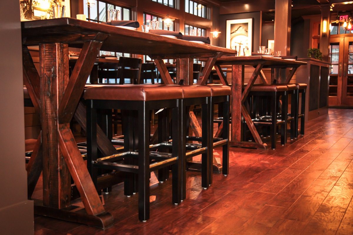 Cozy bar stools lined up along a wooden counter in a warm, inviting pub.