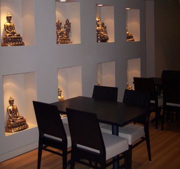 Cozy dining area with Buddha statues in wall niches.