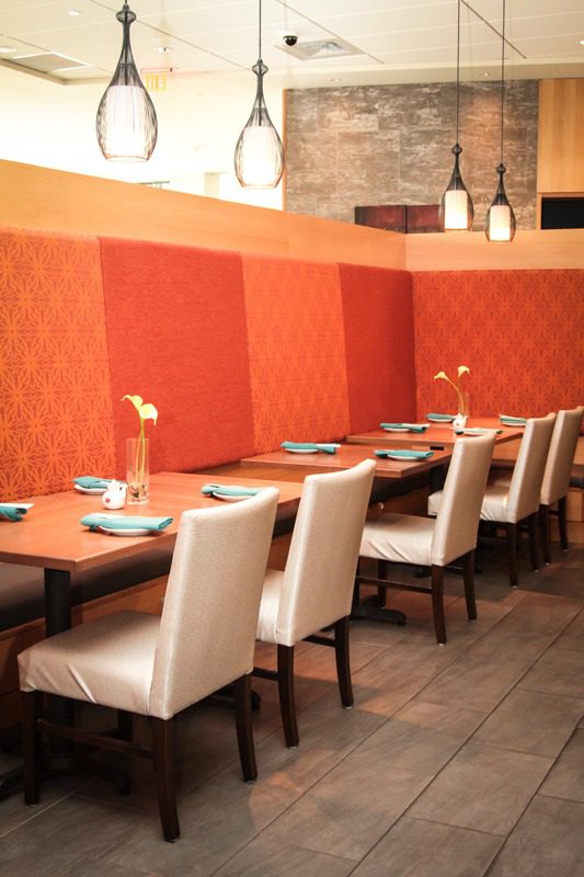 Elegant dining area with orange cushioned walls and white chairs.
