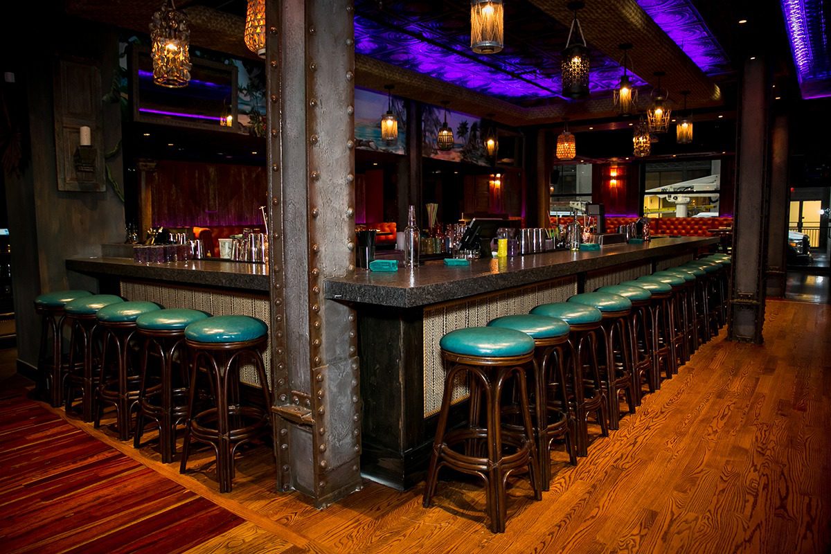 Cozy bar with green stools and warm lighting.