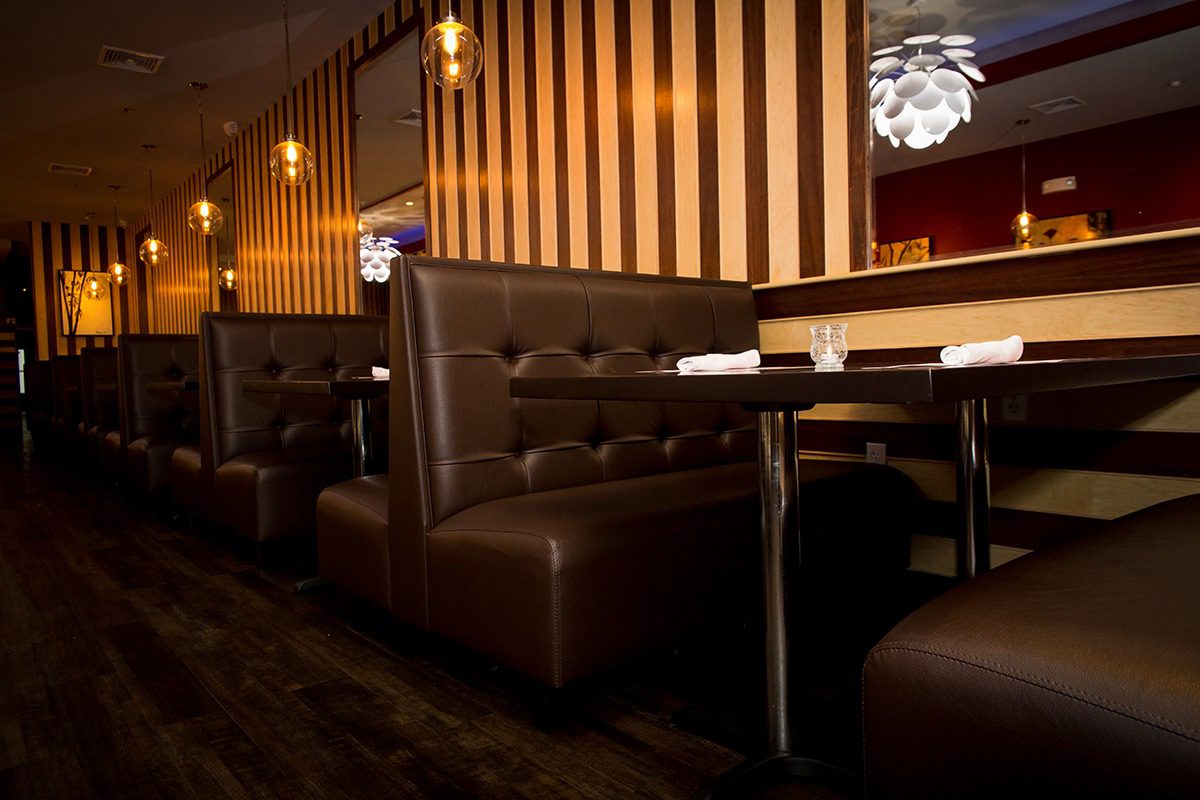 Cozy brown leather booths with striped wallpaper in a warmly lit restaurant.