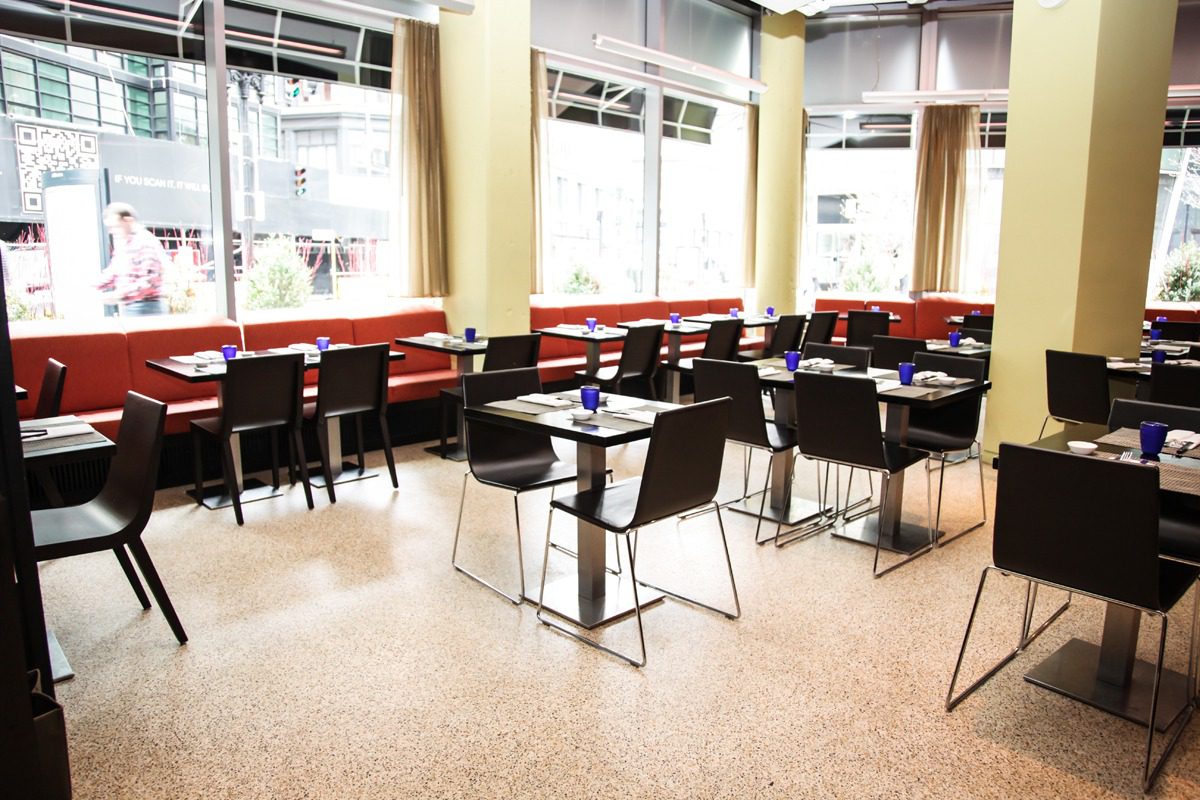 Bright, modern dining area with black chairs and red booth seating.