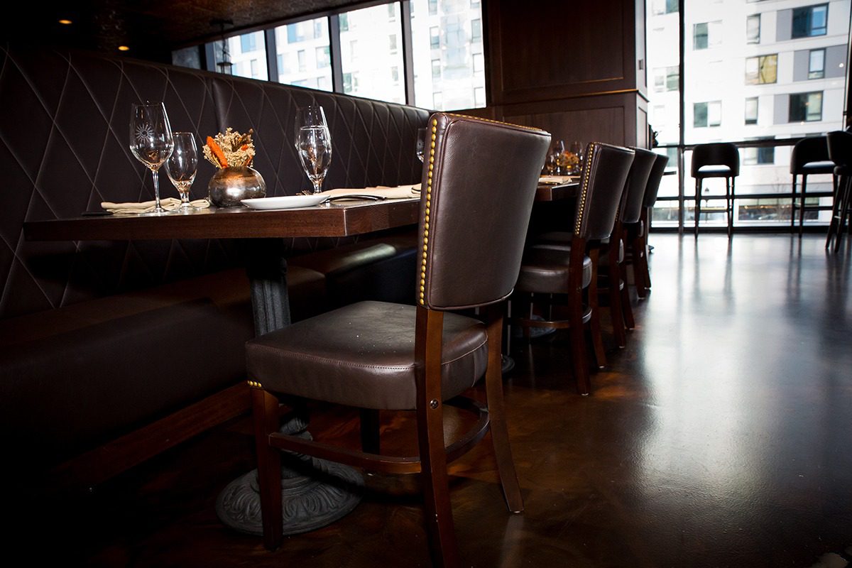 Elegant dining chairs around a polished wooden table in a cozy restaurant.