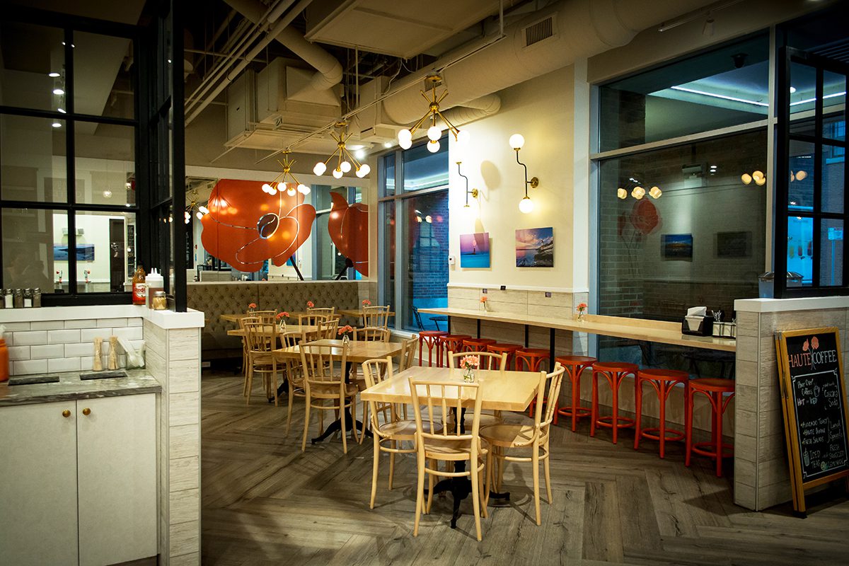 Cozy modern cafe interior with wooden tables and hanging lights.