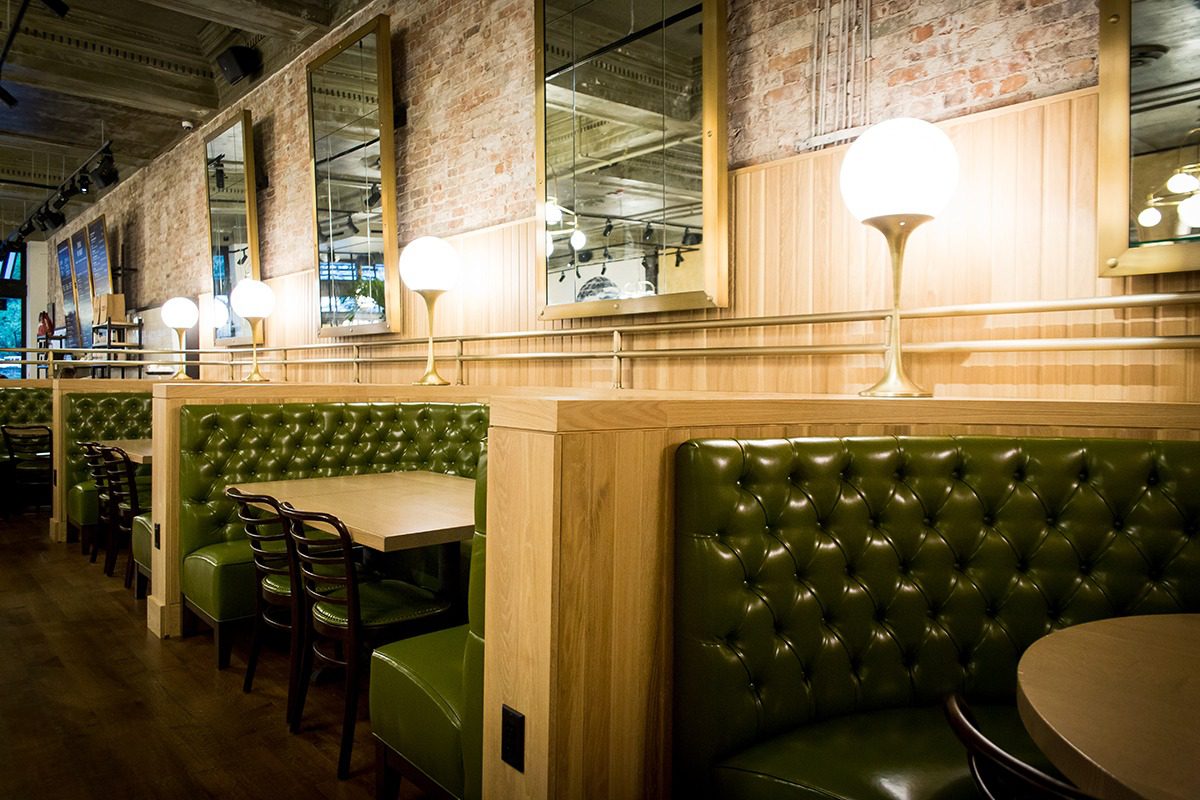 Cozy restaurant booth seating with tufted green upholstery and warm lighting.