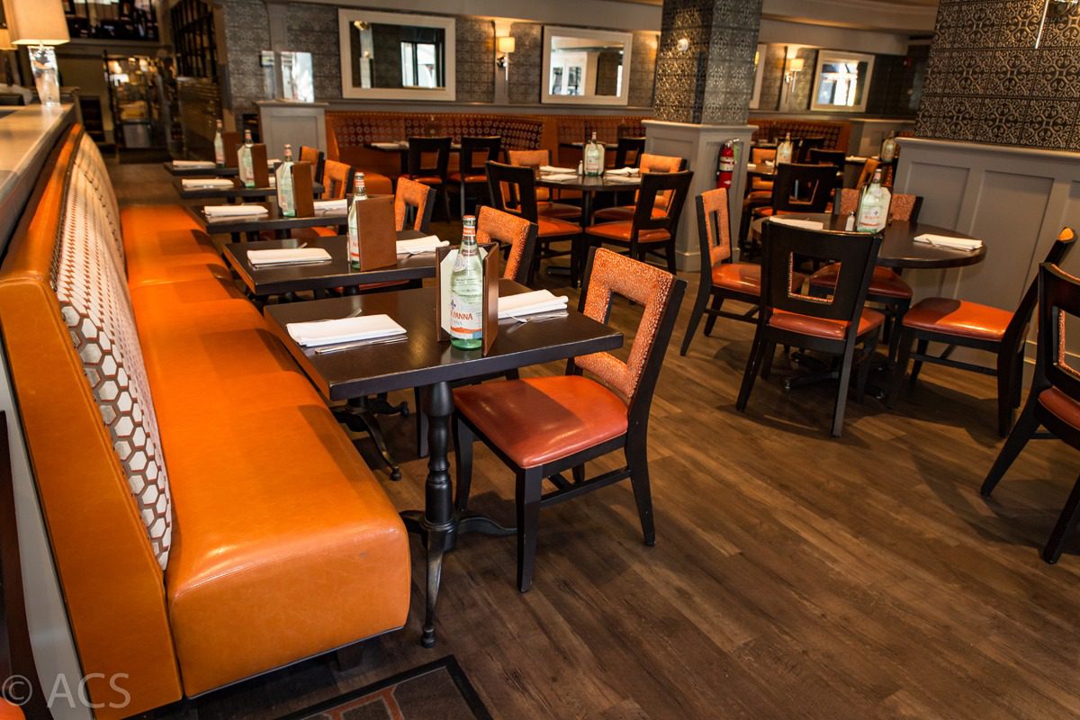 Cozy restaurant interior with orange cushioned seating and wooden tables.
