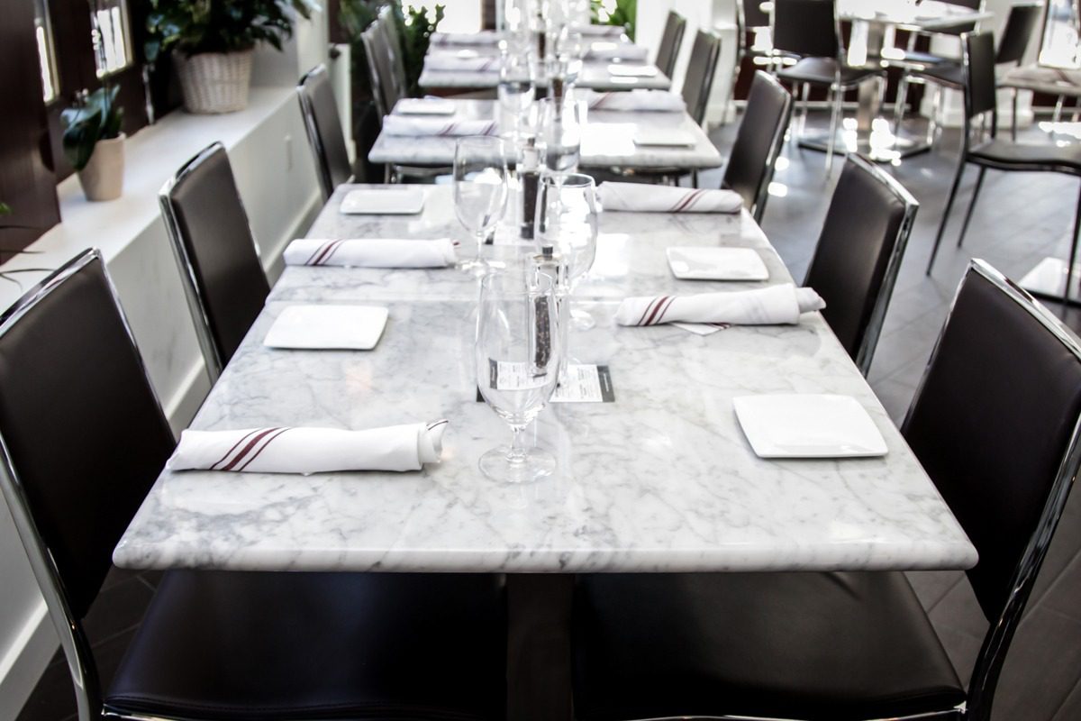 Elegant marble dining table set with white napkins and glassware.