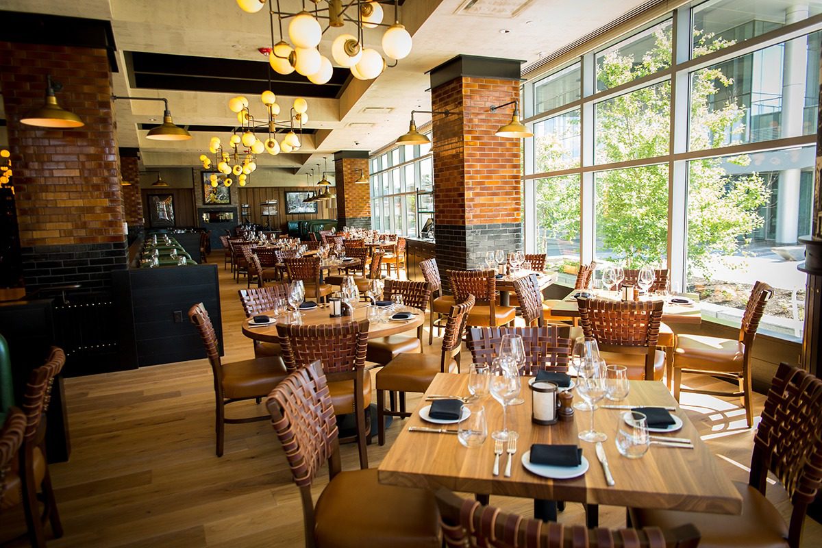 Bright and cozy restaurant interior with wooden tables and large windows.