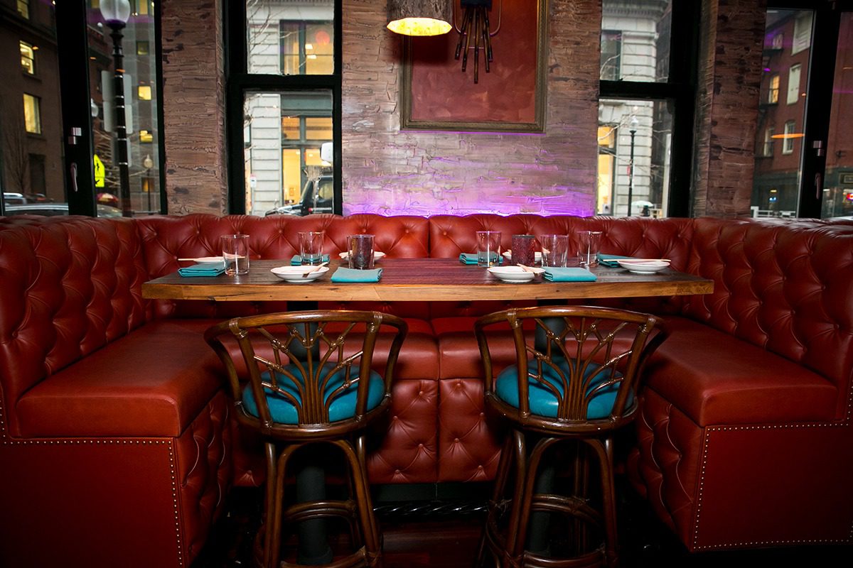 Cozy bar seating with tufted leather benches and wooden stools.
