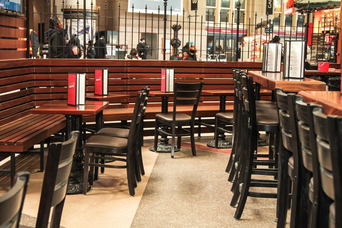Empty wooden chairs and tables in a sunlit café or restaurant.