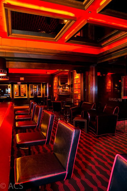 Cozy dimly lit bar with red and wooden decor and high chairs.