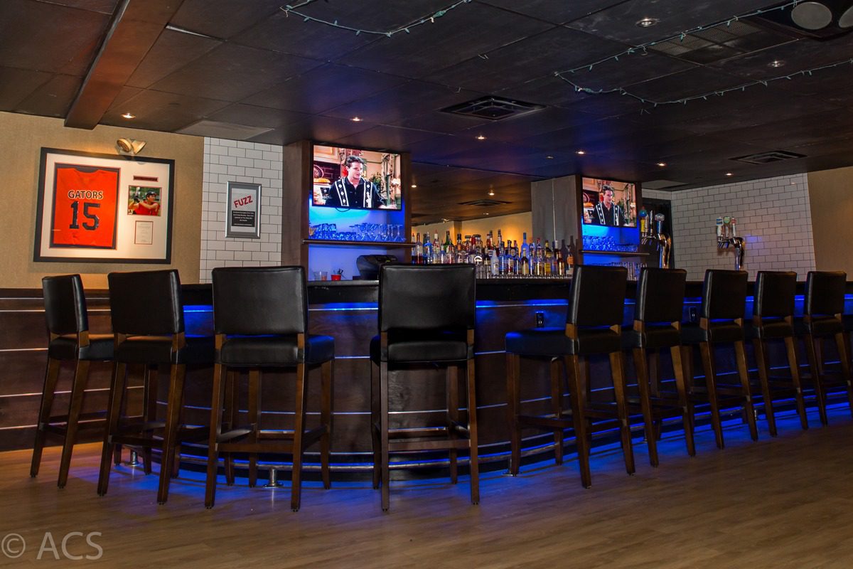 Cozy bar interior with high chairs and a well-lit counter.