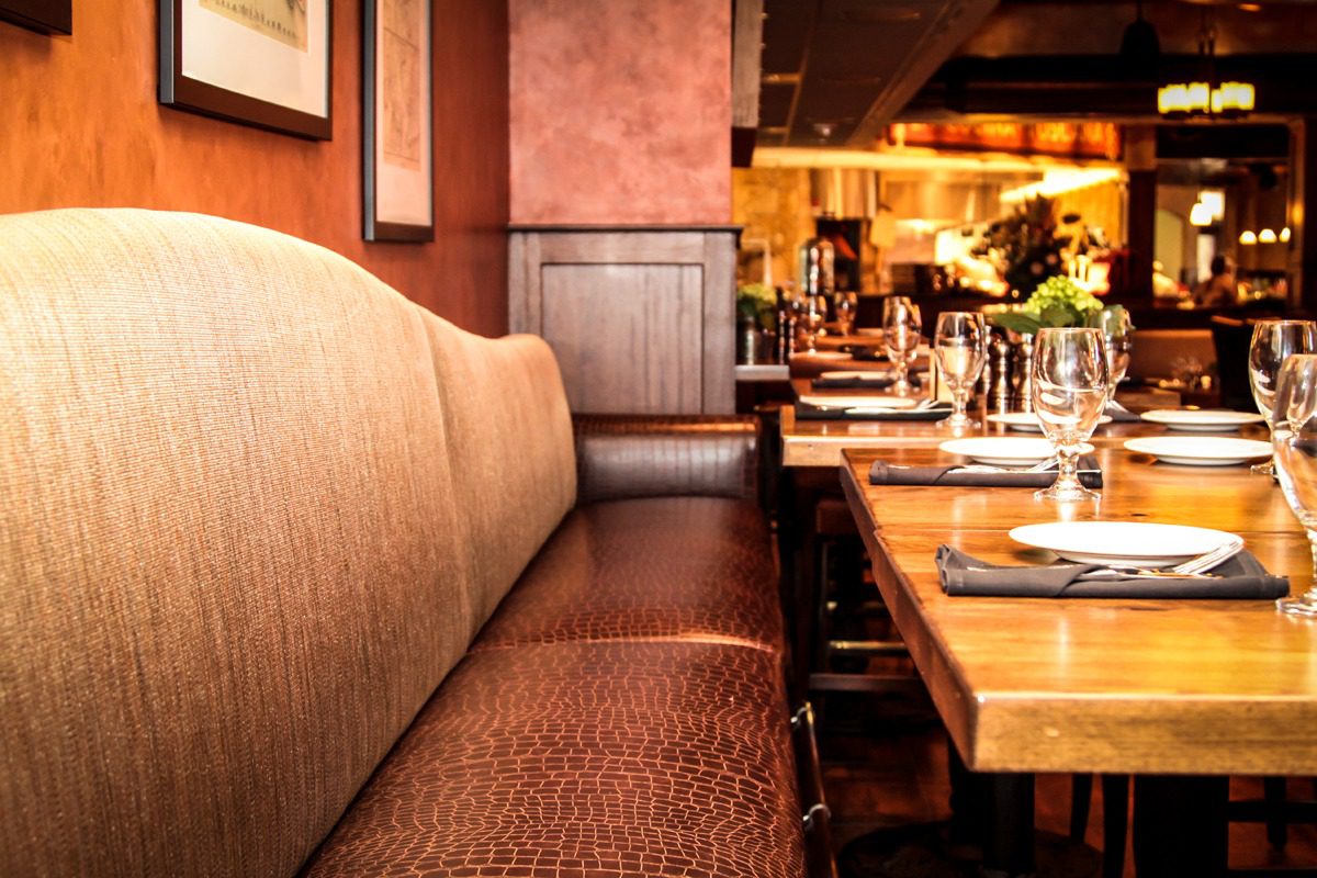 Cozy restaurant booth with warm lighting and a wooden table set for dining.