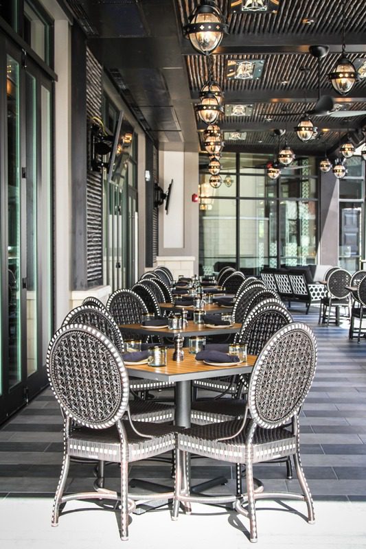 Elegant outdoor dining area with classic round tables and patterned chairs.