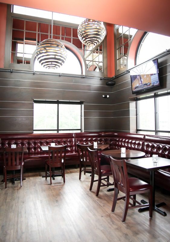 Elegant restaurant interior with dark wood and red leather seating.