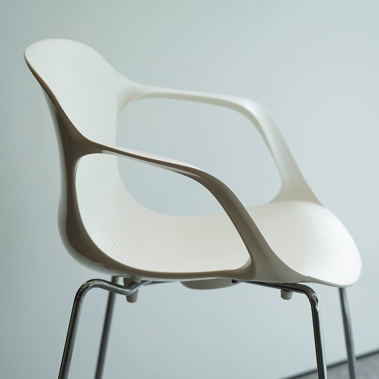 Modern white chair with sleek armrests and metal legs.