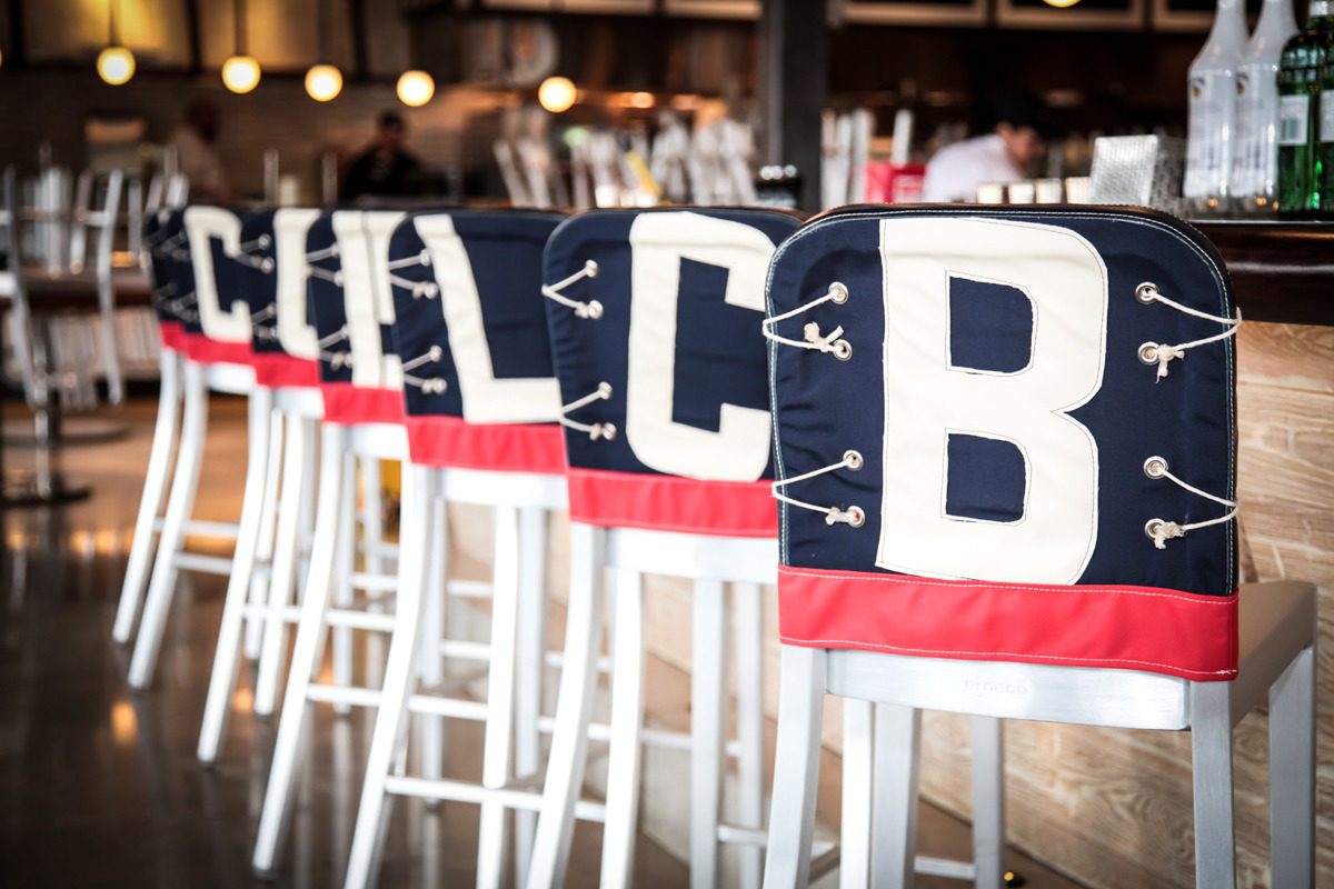 Nautical-themed chair covers with anchors and letters on white chairs.
