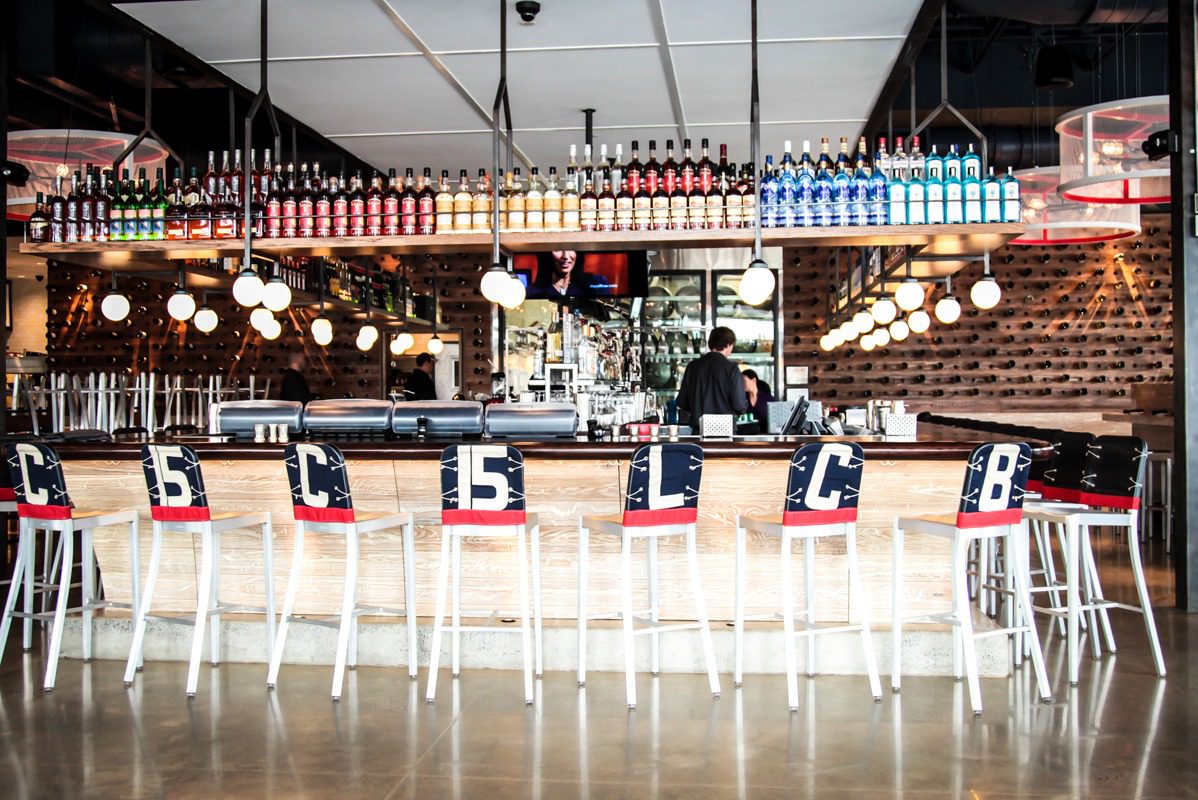 Modern bar interior with numbered seats and hanging bottles.