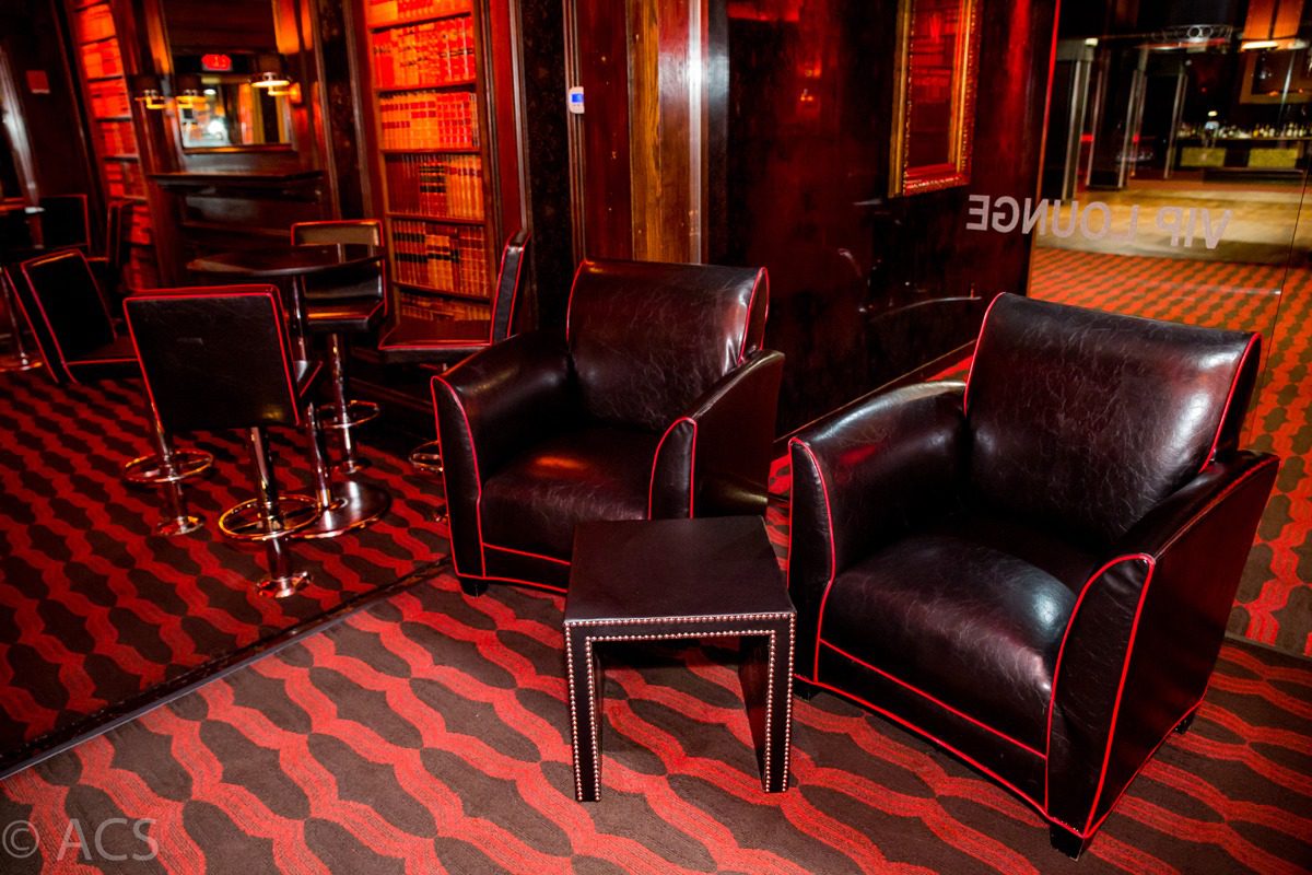 Cozy leather armchairs and a small table in a warmly lit lounge with wooden decor.