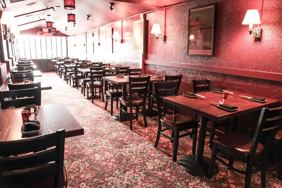 Empty rustic restaurant with wooden chairs and tables.